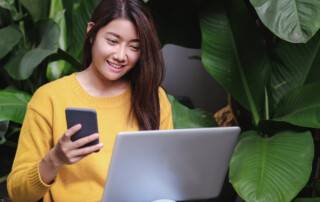 woman holding phone and laptop